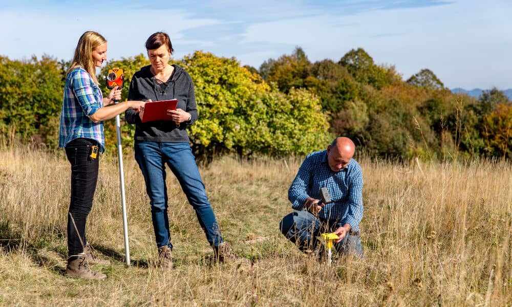 Surveyors working together to mark a boundary during a property line survey in an open field