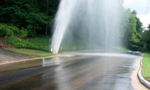 Flooded city street caused by a water main break, showing why a construction survey is critical for verifying underground utilities and reducing repair risks