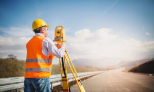 Licensed land surveyor conducting a topographic survey with a total station in Oklahoma City.