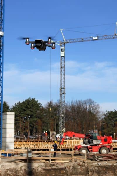 Survey drone flying over active construction site to collect aerial data for ALTA Land Title Survey and infrastructure planning
