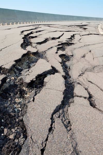 Ground cracks in pavement caused by earthquake, showing why homeowners should consider a property survey

