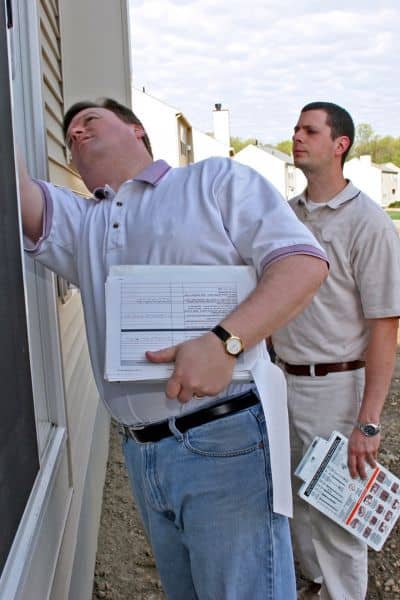 Property inspection surveyors documentation - ALTA SURVEY Oklahoma Two land surveyors inspecting a residential property to verify elevation data and update a flood elevation certificate