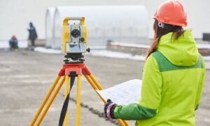 A commercial property surveyor reviewing survey data on an active site before closing