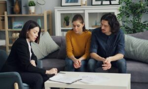 Homebuyers reviewing closing documents with their real estate agent during a delayed transaction caused by missing elevation certificates