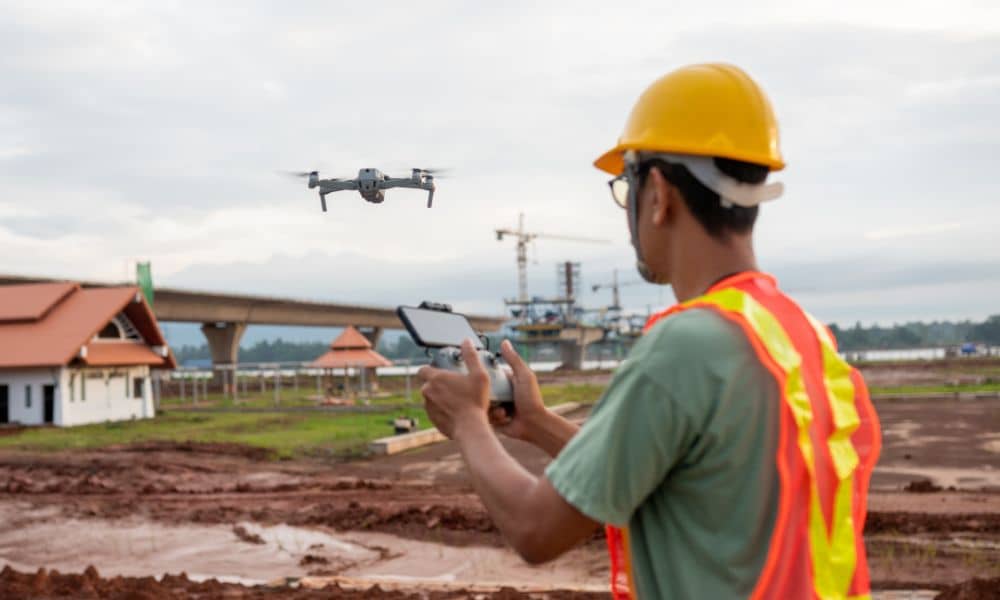 Licensed land surveyor operating a drone over an active construction site to collect topographic data
