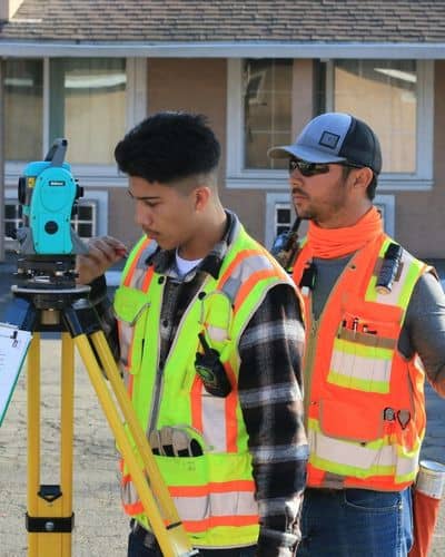 Surveyor measuring ground levels near a residential home after a storm for an elevation certificate