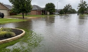 Flooded residential street after a heavy storm with water pooling near homes and driveways