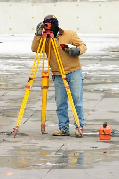 Surveyor performing field work with a total station during an ALTA land survey for commercial property verification