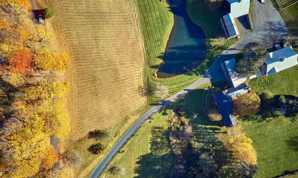 Aerial view of a rural property with several buildings, a driveway, and surrounding farmland, providing a clear view of the property for a property line survey