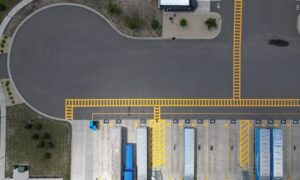 Aerial view of a commercial loading dock and truck court with paved loading areas and marked access lanes, as shown when reviewing site conditions for a flood elevation certificate